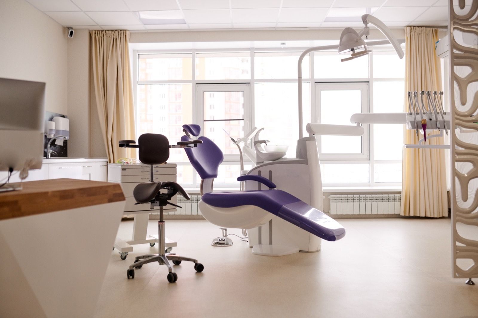 A dental treatment room, with the chair and overhead lamp beside a bright window