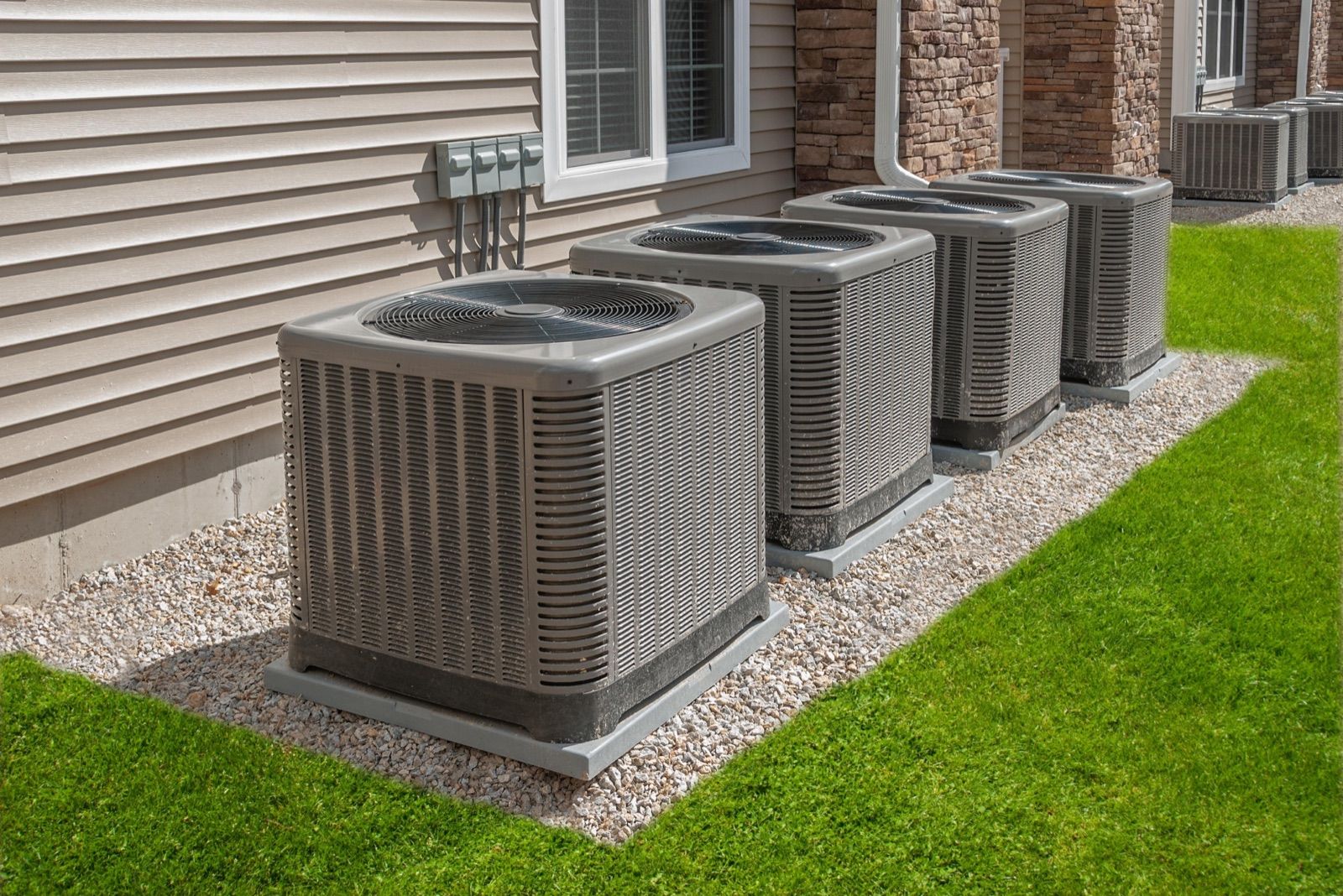 A row of air-conditioning condenser units beside a house
